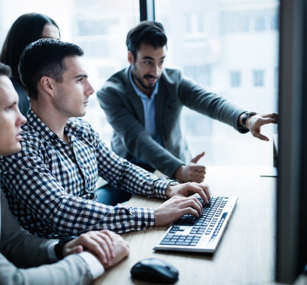 Image of corporate professionals looking at computer monitor together